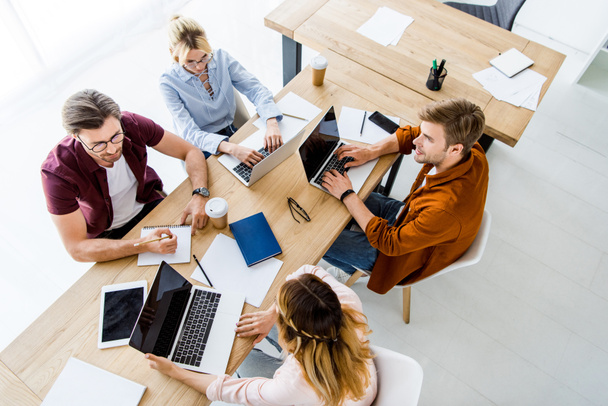 stock-photo-high-angle-view-colleagues-working-startup-project-office-laptops